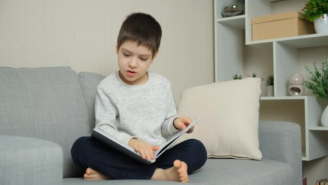 Cute 6 year old child flipping through a book, looking at pictures and learning to read.