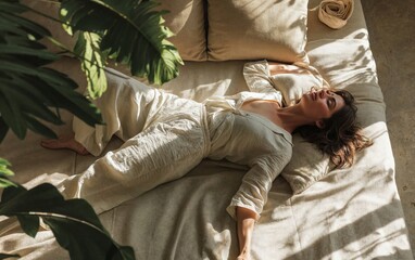 Fototapeta na wymiar Relaxed woman lying down on a linen couch surrounded by plants, basking in sunlight, evoking a serene indoor oasis