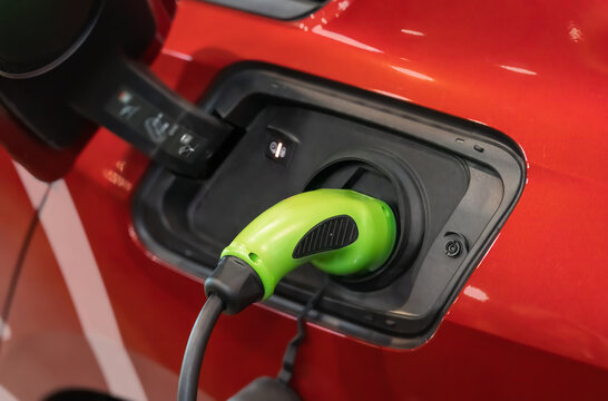 Electric car (EV) is charging in socket with cable.