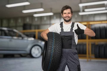 Tapeten Car mechanic is holding tire in hand and is ready for changing tires. © vchalup