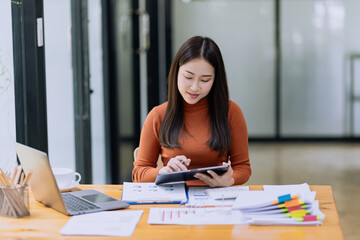 Happy asian accounting businesswoman working with tablet in office working space, Asian female employee using laptop at workplace.