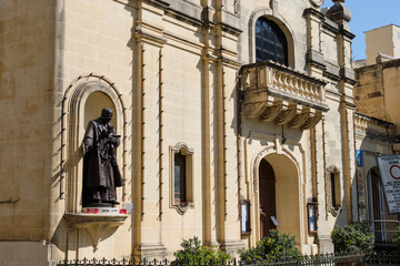 Obraz premium The life-size bronze statue&nbsp;of San George Preca, the founder of the Society of Christian Doctrine as well as a Third Order Carmelite, on the façade of St James Church - Victoria, Malta
