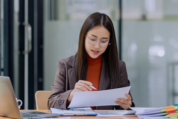 Happy asian young businesswoman with documents folders sitting in office working space, Asian...