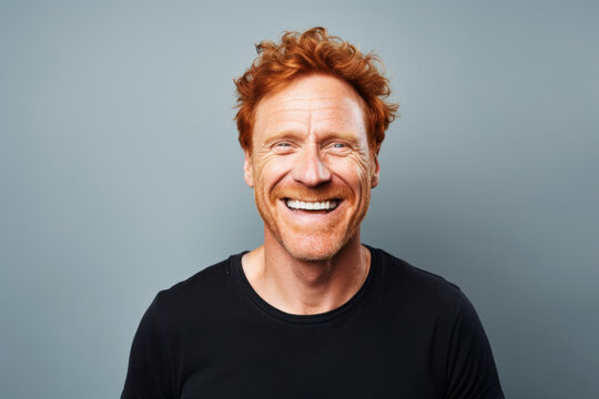 Confident Middle-aged Redhead Man Laughing Against Dark Blue Wall with Copy Space