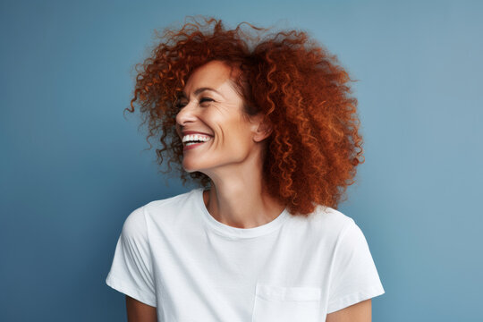Vibrant Middle-aged Redhead Woman Laughing Against Blue Background with Copy Space