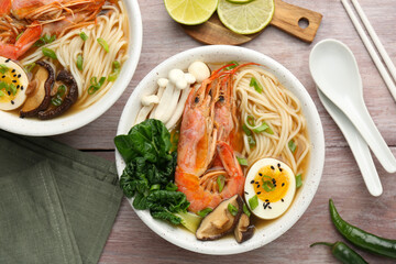 Delicious ramen with shrimps in bowls served on wooden table, flat lay. Noodle soup