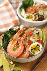 Delicious ramen with shrimps and egg in bowl served on table, closeup. Noodle soup