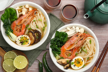 Delicious ramen with shrimps in bowls served on wooden table, flat lay. Noodle soup