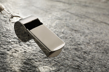 Referee equipment. Metal whistle on grey textured background, closeup and space for text
