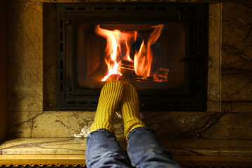 Woman in warm socks resting near fireplace indoors, closeup