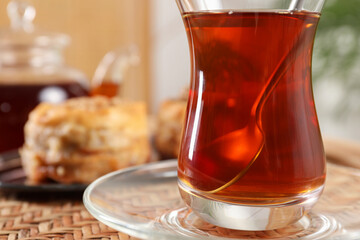 Traditional Turkish tea in glass on wicker table, closeup. Space for text
