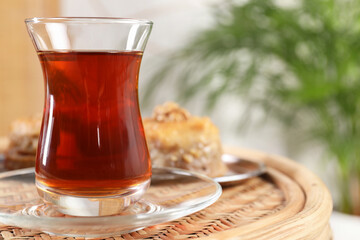 Traditional Turkish tea in glass on wicker table, closeup. Space for text