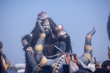 Masan Holi, Portrait of an male artist act as lord shiv with dry ash on face and body also in air while celebrating the holi festival as tradition at Harishchandra ghat in varanasi, India. - obrazy, fototapety, plakaty