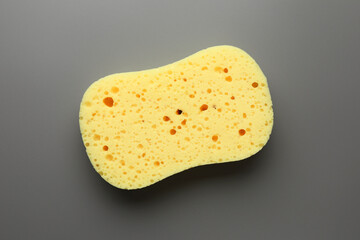 New yellow sponge on grey background, top view