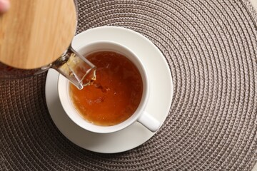 Pouring aromatic tea into cup at table, top view. Space for text
