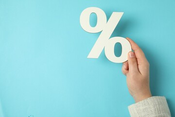 Man holding percent sign on light blue background, top view. Space for text