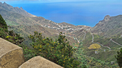 panoramic view from above of a mountainside town and serpentines leading to it with ocean in the background in Tenerife