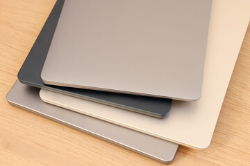 Different modern laptops on wooden table, closeup