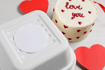 Bento cake with text Love You and takeaway packaging on white table