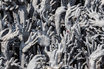 Sculpture de mains de pierre sortant du sol et symbolisant la souffrance humaine et l'enfer