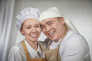 Cute oriental family with wife and husband cooking in the kitchen on Ramadan, Kurban-Bairam, Eid al-Adha. Funny couple of cooks at joke photo shoot. Pancakes, pastries, Maslenitsa, Easter