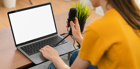 Woman hand type on the keyboard on laptop with mockup of blank screen and microphones for record...