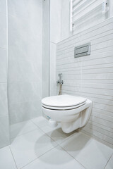 Modern bathroom interior with white toilet bowl, bidet, and ceramic tiles.