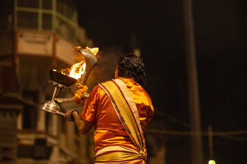 Ganga aarti, Portrait of young priest performing holy river ganges evening aarti at dashashwamedh ghat in traditional dress with hindu rituals.