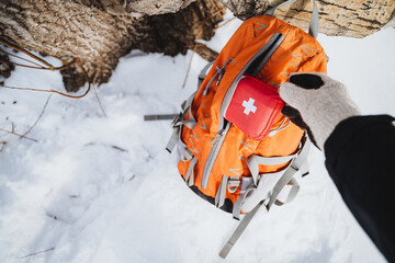 Taking first aid kit from backpack while camping in snowy weather conditions