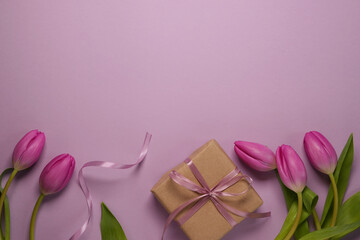Mother's Day or International Womens-day concept. Top view flat lay of present boxes with ribbon, tulip flowers on a soft pastel violet background with space for text or advert.