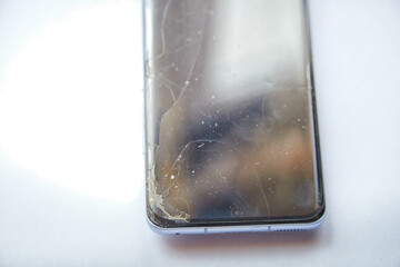 Close-Up View of a Cracked Smartphone Screen Against White Background. the detailed texture of a shattered smartphone screen, emphasizing the extensive damage to the device