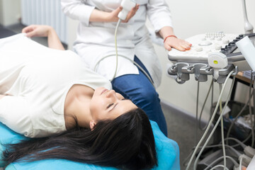 Obraz premium Ultrasound scanning diagnostic of woman thyroid gland in clinic, doctor runs ultrasound sensor