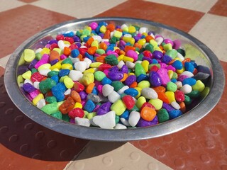 Beautiful multi-colored small rocks and pebbles in the steel bowl. Colorful stones in different size and colors. Decorative item.