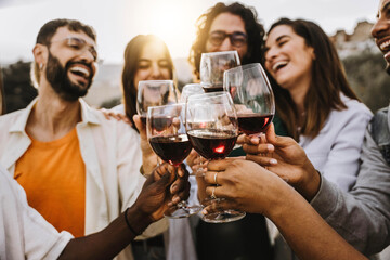 Happy friends toasting red wine glasses outside - Group of young people having bbq dinner party in backyard house - Winery and bbq dining concept with guys and girls cheering alcohol together - obrazy, fototapety, plakaty