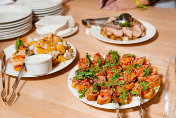 Catered Buffet Spread with Assorted Appetizers. A buffet table featuring a spread of appetizers, including bruschetta topped with tomato and arugula, skewered grilled vegetables, and sliced roasted me