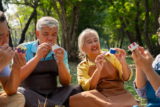 A group of Asian senior people enjoy painting cactus pots and recreational activity or therapy outdoors together  at an elderly healthcare center, Lifestyle concepts about seniority - Powered by Adobe