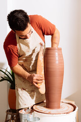 Male potter standing in studio creating clay vase