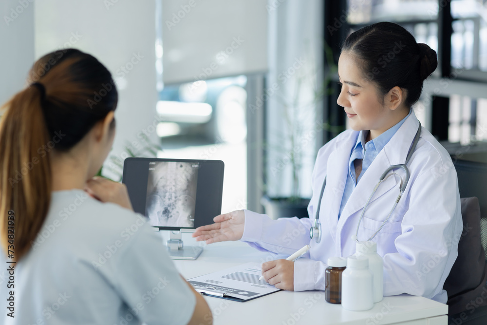 Wall mural Asian female doctor explain to patient and looking at xrays indoors office, healthcare and medical concept.