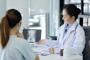 Asian female doctor explain to patient and looking at xrays indoors office, healthcare and medical...