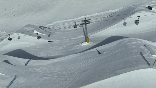 Aerial drone view of Madonna di Campiglio and ursus snowpark in Val Rendena dolomites trentino Italy. Snowboarder skier jumps on kicker in snowpack.
