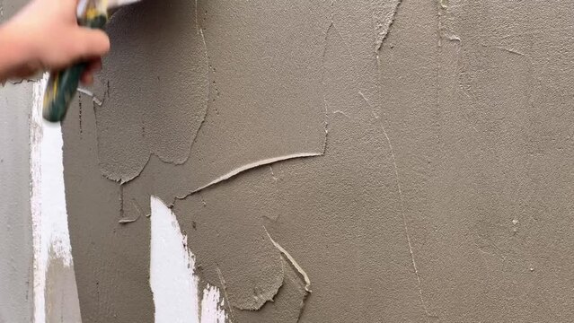 Close-up of a worker's hand with a trowel. Applying mortar to reinforcing mesh and rigid polyurethane foam for home insulation. External construction work.