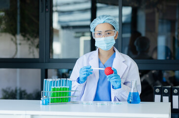 Asian female scientist or medical technician working with a blood lab test in the research lab,...