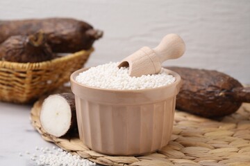 Tapioca pearls in bowl and cassava roots on wicker mat