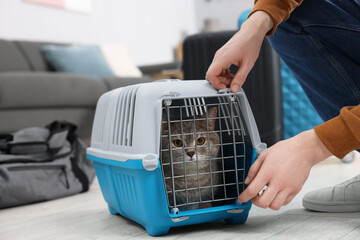 Travel with pet. Man closing carrier with cat at home, closeup