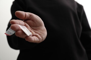Drug addiction. Man with plastic bag of cocaine on light background, closeup