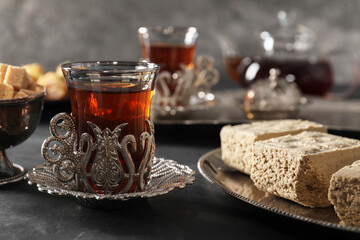 Turkish tea and sweets served in vintage tea set on black table, closeup