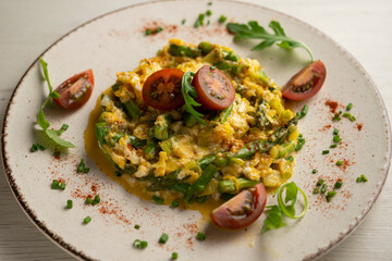 Scrambled eggs with green asparagus and cherry tomatoes.