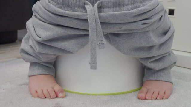 bare feet of child little boy sitting on a potty closeup