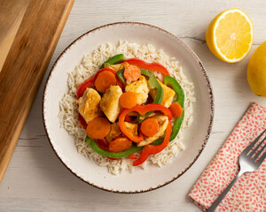 Chicken cooked in a wok with colorful peppers and rice.