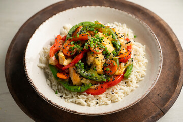 Chicken cooked in a wok with colorful peppers and rice.